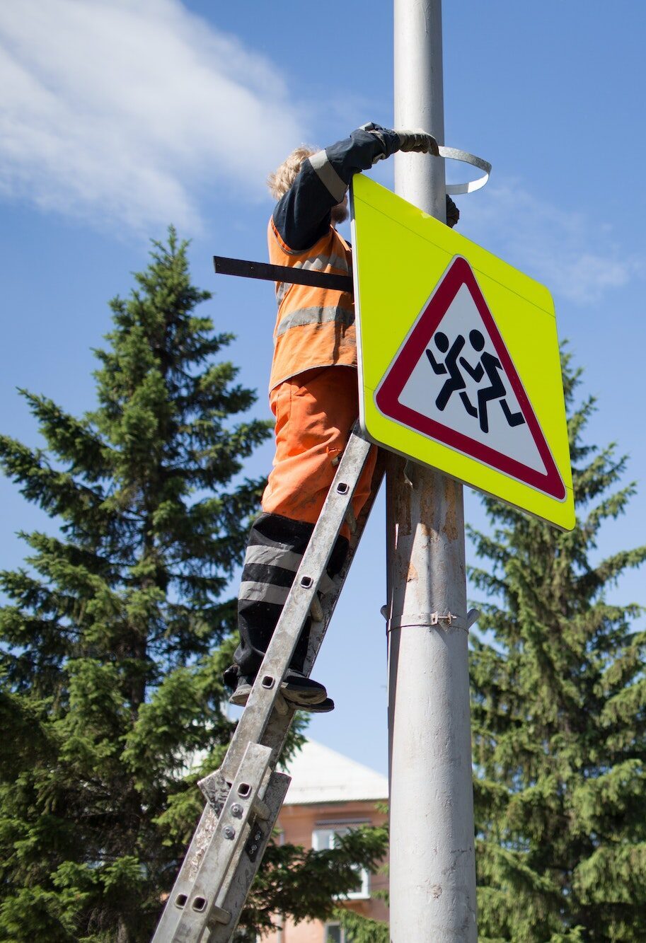 Installation road sign on pole. Road worker sets sign.